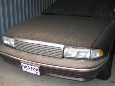1991 Ford LTD Crown Victoria - Photograph of a dust-covered Chevrolet sedan front end with a Hilltop dealer license plate.