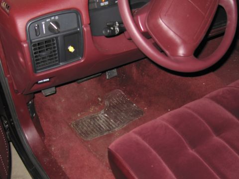 1991 Ford LTD Crown Victoria - Photograph of a red car interior showing the steering wheel, HVAC controls, and floor.