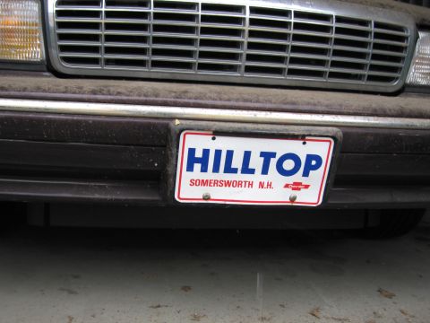 1991 Ford LTD Crown Victoria - Photograph of a vehicle front grille and dealer plate, not a technical document.