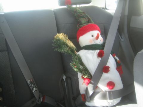 1968 Ford Mustang - A festive snowman is buckled into a car seat, ready for a holiday journey.