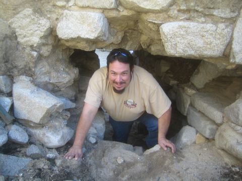 1968 Ford Mustang - A man is crawling through a narrow opening in a stone structure.