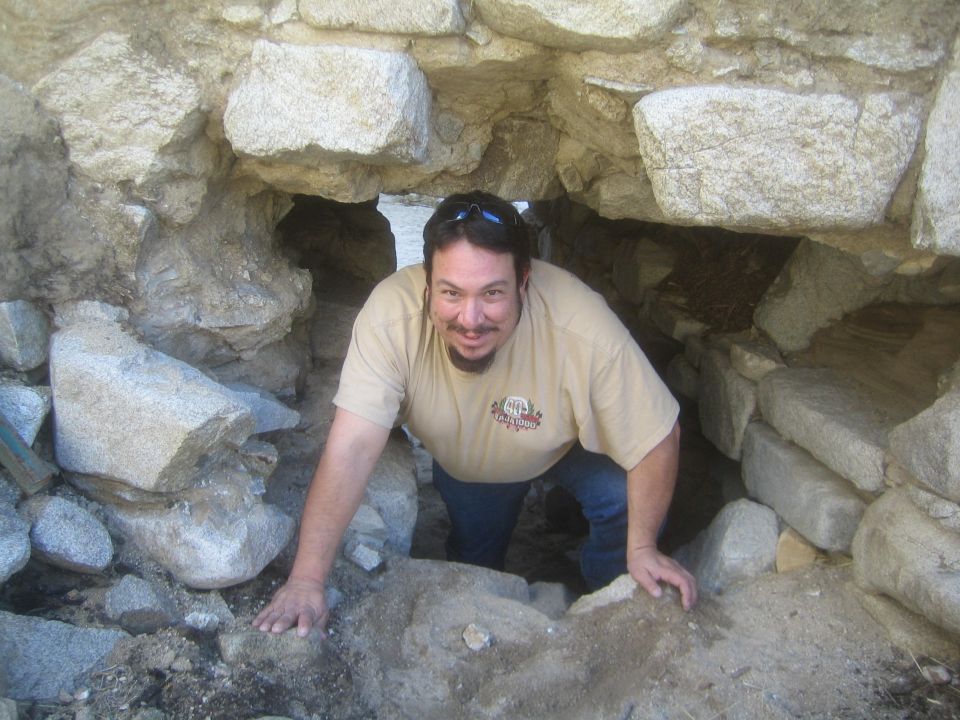 guy climbing through a rocky tunnel opening