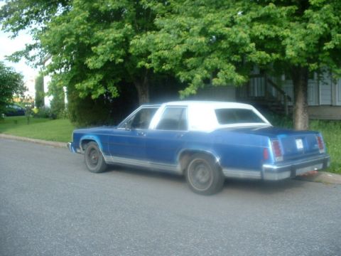 1987 Ford Crown Victoria LTD - Side view of a blue 1987 Ford Crown Victoria LTD sedan with a white roof parked on a residential street.