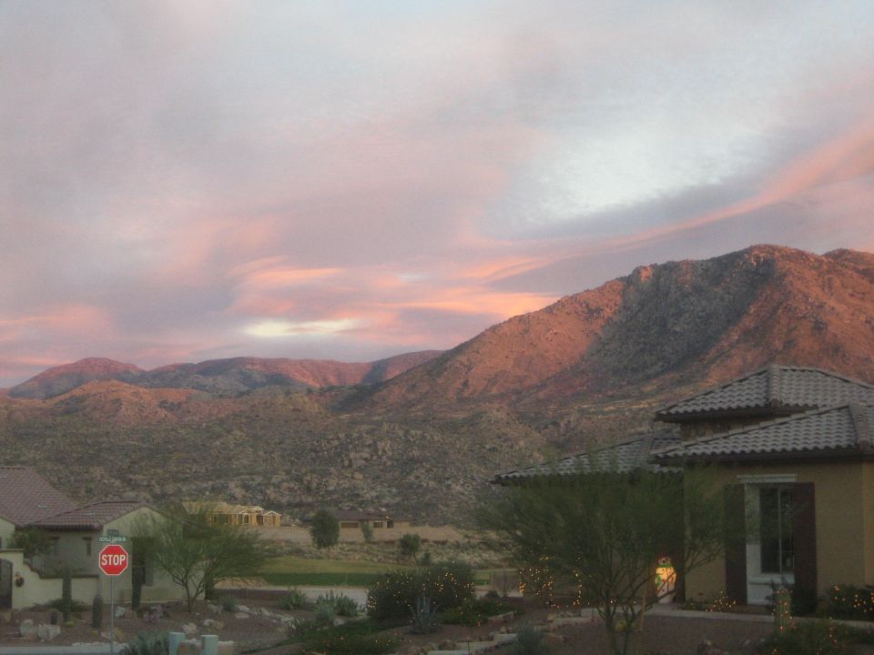 Desert mountains at sunset with houses and a stop sign in the foreground