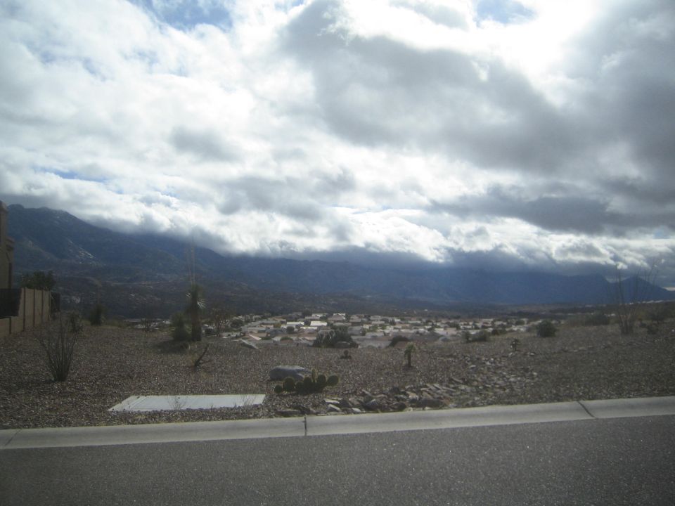 View of a desert town with mountains in the background under a cloudy sky