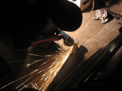 1989 Ford Bronco - Grinding sparks fly as a person works on a vehicle's exhaust system in a garage.