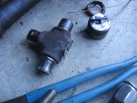1989 Ford Bronco - Close-up of a universal joint and a damaged bearing cap, likely for a vehicle axle rebuild.