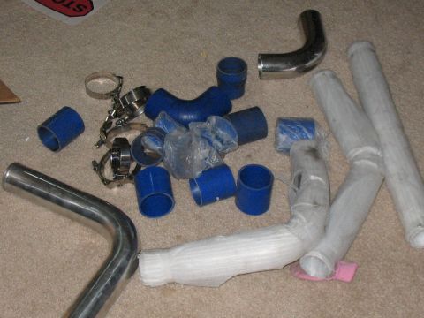 2001 Pontiac Trans Am - Turbo plumbing parts including silicone couplers, metal pipes, and clamps are laid out on a carpeted surface.