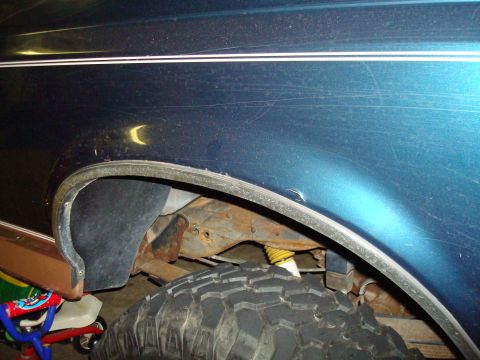 1995 Ford Bronco - The photo shows the rear wheel well of a vehicle, with visible rust on the suspension components and a portion of the tire.