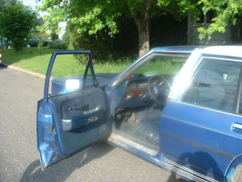 1987 Ford Crown Victoria LTD - The interior of a blue sedan is visible with the driver's side door ajar.