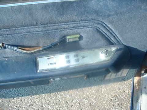1987 Ford Crown Victoria LTD - Close-up of a worn car door interior, showing fabric upholstery and control buttons.