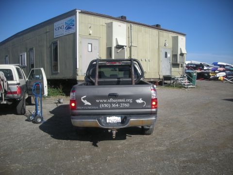 1991 Ford Bronco - Straight-on rear view of a gray Toyota Tundra i-Force V8 double-cab pickup on a gravel lot outside the Marine Science Institute building, w…