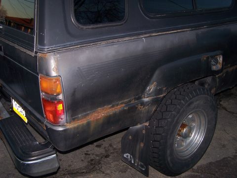 1988 Toyota Pickup/SR5 - Rear view of a 1988 Toyota Pickup/SR5, highlighting rust damage and a fitted camper shell.