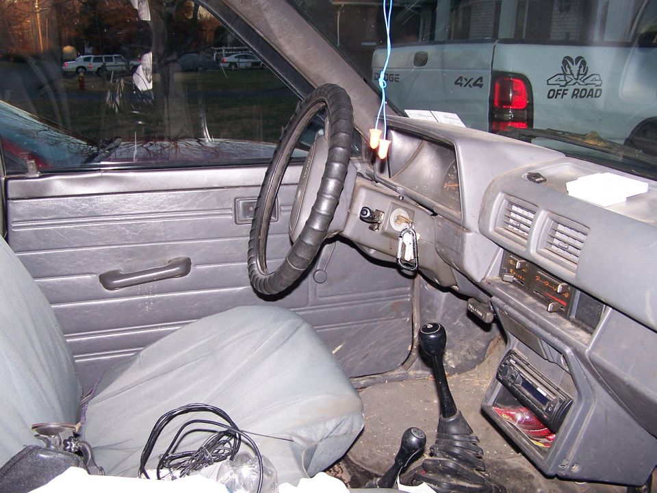 Gray pickup interior with wrapped steering wheel, dual floor shifters and aftermarket CD stereo