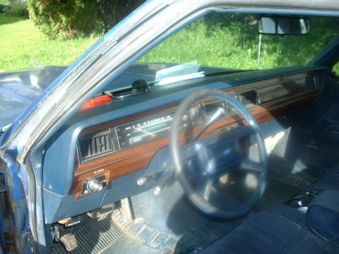 1987 Ford Crown Victoria LTD - The interior of a blue vehicle is shown, a wood-grain dashboard and a large steering wheel.