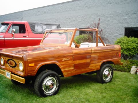 1995 Ford Bronco - Custom wood-bodied Ford Bronco with a red Ford truck in the background.