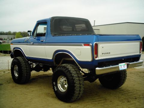 1995 Ford Bronco - This lifted Ford pickup has a two-tone paint job and a soft top covering the rear.