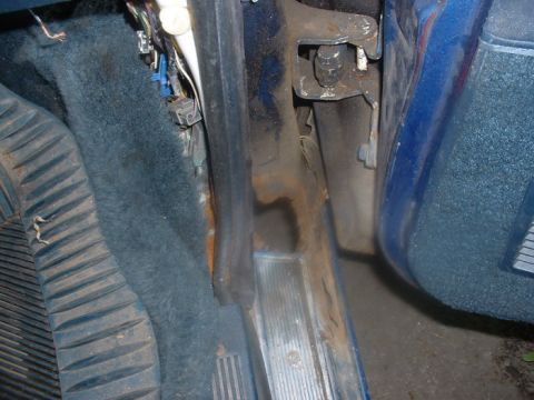 1987 Ford Crown Victoria LTD - Close-up view of the driver's side footwell, showing the pedals, carpet, and door jamb area.