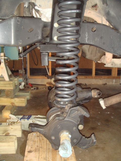 1992 Ford Bronco - The image shows a disassembled vehicle suspension system, including a coil spring and axle components, in a workshop setting.