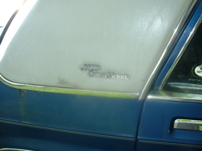 Close-up of the LTD Crown Victoria badge on a blue car with a white vinyl top