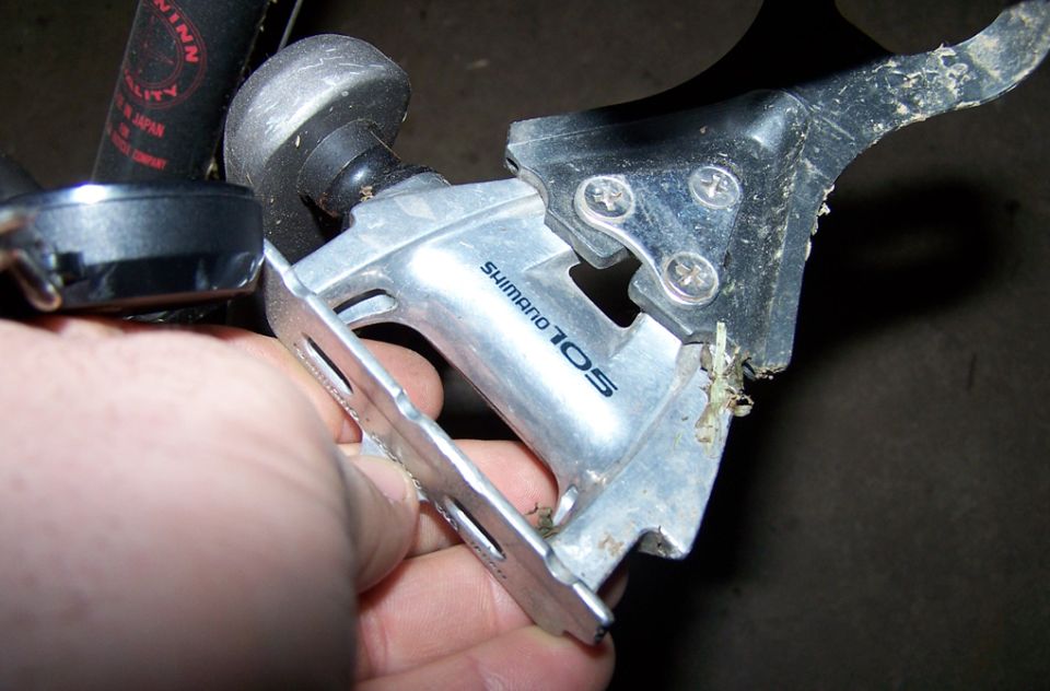 Hand holding a Shimano 105 derailleur, part of a bicycle