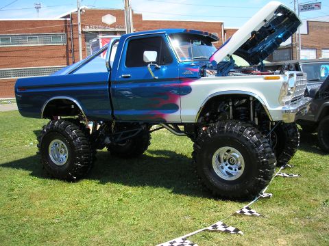 1995 Ford Bronco - This heavily modified pickup truck features a two-tone paint scheme with flame graphics and oversized off-road tires.