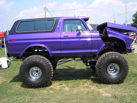 1995 Ford Bronco - This modified Ford Bronco features a significant lift kit and oversized tires, with its hood open.