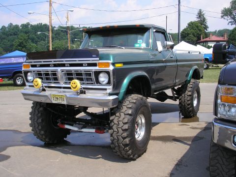 1995 Ford Bronco - A lifted Ford truck with a custom paint job and prominent smiley face fog lights is parked outdoors.
