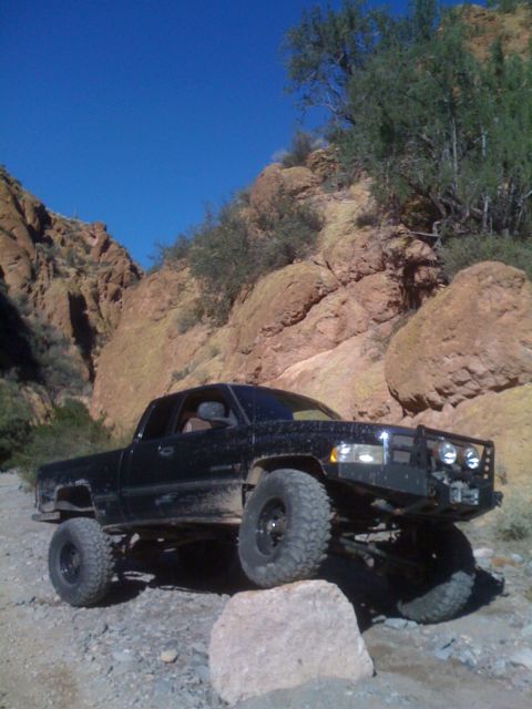 1966 Ford Bronco - Pickup truck navigating a challenging rocky terrain under a clear blue sky.