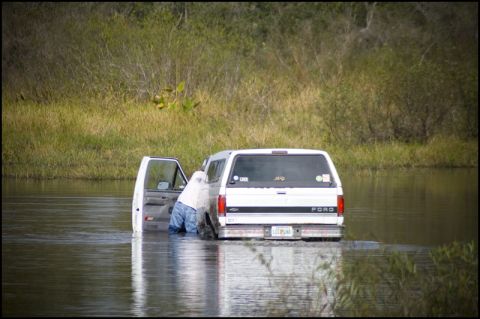 1996 Ford F-150 - A white Ford van is partially submerged in water, with its driver's side door open and a person inside.