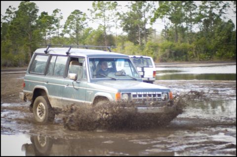 1996 Ford F-150 - A Mitsubishi Montero splashes through mud, with another vehicle visible in the background.