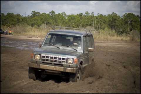 1996 Ford F-150 - A gray Mitsubishi Montero navigates through a muddy off-road course.