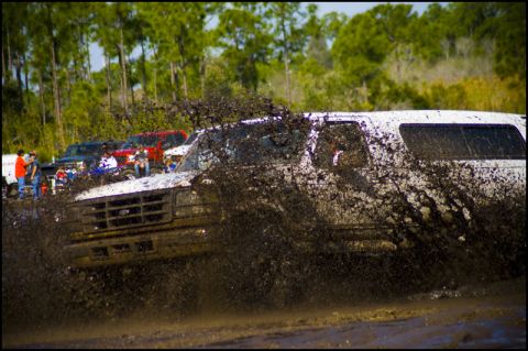 1996 Ford F-150 - A white SUV navigates a muddy track, kicking up a large spray of dirt and water.