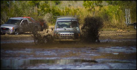 1996 Ford F-150 - Vehicles navigate a muddy track, creating large splashes as they go.