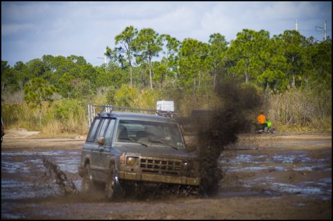 1996 Ford F-150 - An SUV navigates a muddy obstacle course, emitting a cloud of dark exhaust.