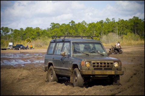 1996 Ford F-150 - Off-road vehicle navigating a muddy terrain with other vehicles present in the background.