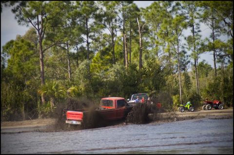 1996 Ford F-150 - Multiple vehicles navigate a muddy track with ATVs waiting on the side.