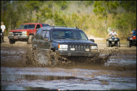 1996 Ford F-150 - Off-roading fun with multiple vehicles navigating a muddy terrain.