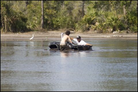 1996 Ford F-150 - An ATV is stuck in the water with two people inside.