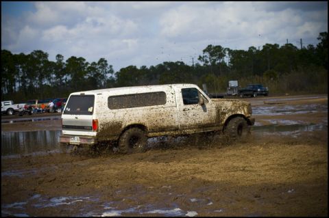 1996 Ford F-150 - Muddy 1996 Ford Bronco with camper shell navigating a muddy track.