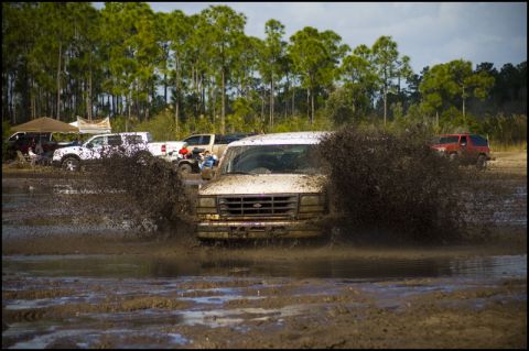 1996 Ford F-150 - A white van navigates a muddy track, sending brown water and mud flying.