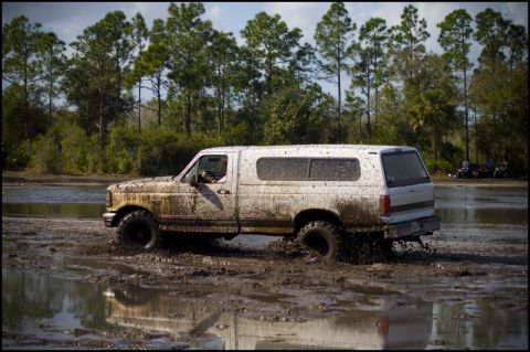 1996 Ford F-150 - This 1996 Ford F-150 navigates a muddy terrain, its white paintwork heavily caked with mud.