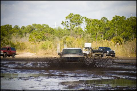 1996 Ford F-150 - A white Ford E-Series van navigates a muddy obstacle course with other vehicles nearby.