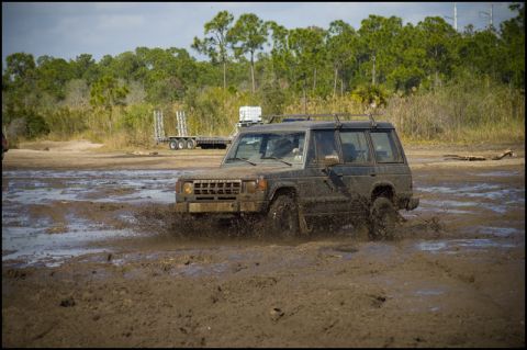 1996 Ford F-150 - SUV navigates a muddy terrain, kicking up water and dirt.