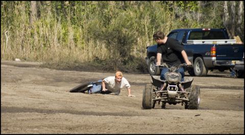 1996 Ford F-150 - A blue pickup truck is parked in a dirt lot while two people are on an ATV and another person is on the ground.
