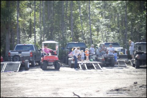 1996 Ford F-150 - People and vehicles are gathered in a dirt lot surrounded by trees, with ramps set up near some of the trucks.
