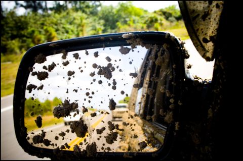 1996 Ford F-150 - The side mirror is covered in mud, obscuring the view of the road and the vehicle behind.