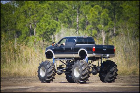 1996 Ford F-150 - A modified pickup truck with oversized tires and suspension is shown off-road.