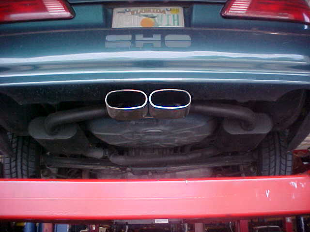 Underside rear of a Ford Taurus SHO on a lift showing dual chrome exhaust tips and SHO badge