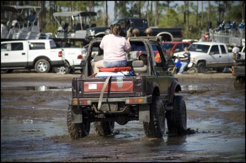 1996 Ford F-150 - A group of vehicles are gathered in a muddy area, with one off-road vehicle in the foreground.